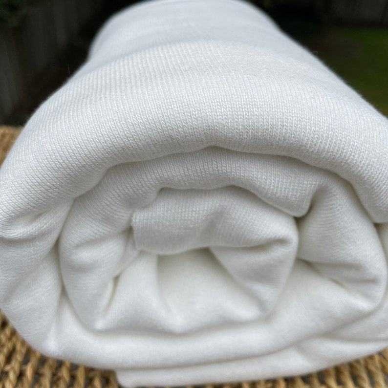 May include: A white, rolled up piece of fabric with a ribbed texture.