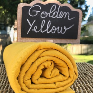 May include: A roll of golden yellow fabric. The fabric is soft and stretchy, and it is perfect for sewing projects.