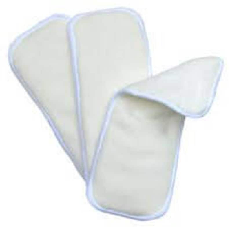 May include: Three white cotton reusable cloth diaper inserts. The inserts are rectangular and have a white trim around the edges.