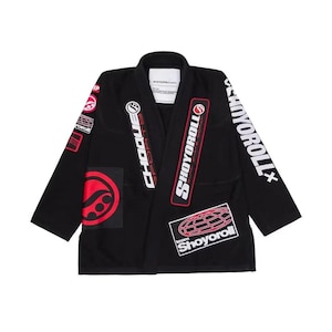 Può includere: Gi di Jiu-Jitsu nero con più toppe con loghi e testo rossi e bianchi. Il gi ha un colletto e maniche lunghe. Le toppe includono "CHOQUE SPORTS", "SHOYOROLL" e un design a globo. Progettato per l'allenamento di arti marziali.