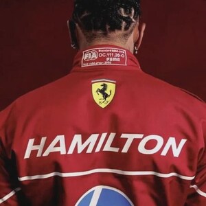 May include: Red jacket with the name "HAMILTON" in white block letters. The jacket features the Ferrari logo, a Puma label, and an HP logo. The back of the jacket is visible.