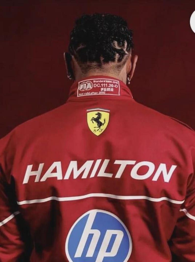 May include: Red jacket with the name "HAMILTON" in white block letters. The jacket features the Ferrari logo, a Puma label, and an HP logo. The back of the jacket is visible.