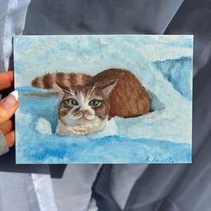 Peinture à l'huile sur toile d'un chat tigré orange dans la neige hivernale