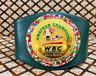 May include: A green leather championship belt with a large gold central emblem. The emblem reads "AMATEUR CHAMPION" and "WBC MUAYTHAI". The belt is trimmed with flags of various nations.