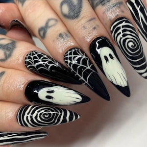 以下が含まれることがあります： 黒と白のハロウィーンをテーマにしたネイルアート。デザインには、クモの巣、幽霊、渦巻き模様が含まれます。爪は長く尖っており、光沢のある仕上がりです。不気味でスタイリッシュなマニキュア。