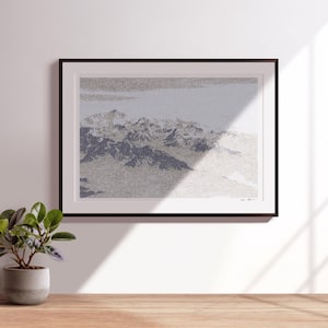 May include: A black framed print of a mountain range with a white background. The mountains are a light blue and gray color. The print is hanging on a white wall.
