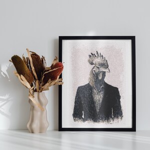 May include: A framed art print featuring a rooster-headed figure in a suit. The artwork is in black and white with a textured effect. A beige vase with dried flowers is to the left of the print. The frame is black, and the background is white.