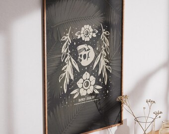Puede incluir: Una impresión enmarcada con una ilustración en blanco y negro de una calavera con flores y hojas. El texto "BORN AGAIN" está debajo de la ilustración. El fondo es un patrón de hojas verdes oscuras.