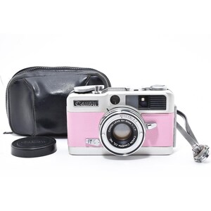 May include: A vintage Canon camera with a pink body and silver accents, lens cap, and a black leather case. The camera has a strap and the Canon logo is visible. A classic photography item.