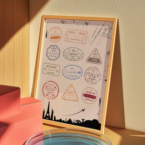 以下が含まれることがあります： モロッコ、イタリア、パリなど、さまざまな場所のパスポートスタンプが特徴の、旅行をテーマにした額入りのアートプリント。木製のフレームの中に、都市景観のシルエットと飛行機が含まれています。