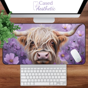 May include: A rectangular mousepad featuring a Highland cow with long, light-colored fur and large horns. The cow is set against a purple background with purple flowers. The mousepad has the text "Cased Aesthetic" in the upper left corner.