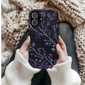 May include: Black phone case featuring a floral design with purple and white accents. The case has a glossy finish and a dual-lens camera cutout. The floral pattern includes branches and leaves, creating an elegant and nature-inspired aesthetic.