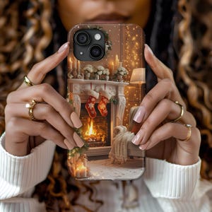 May include: A phone case featuring a festive Christmas scene with a fireplace, stockings, and candles. The case has a brown background with a detailed image of a cozy living room with a lit fireplace and holiday decorations.