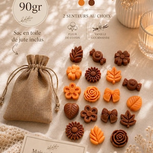 Puede incluir: Una colección de pequeñas ceras aromáticas moldeadas en tonos naranja y marrón, con formas de flores, hojas, lazos y caramelos. Se incluye una bolsa de yute con cordón, etiquetada 90gr. El texto incluye Maison Melunah, 2 COULEURS y 2 SENTEURS AU CHOIX.