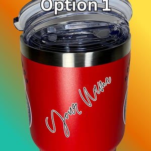 Puede incluir: Un vaso t&eacute;rmico rojo con tapa transparente. El vaso tiene el texto "Option 1" en la tapa y "Your Name" en cursiva en el lateral. Tiene un borde negro y dise&ntilde;os de estrellas.