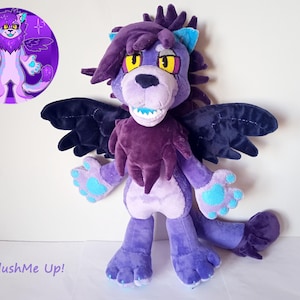 May include: Purple and blue plush toy with wings, a long mane, and a toothy grin. The toy is standing on a white surface. The text "PlushMe Up!" is visible in the bottom left corner of the image.
