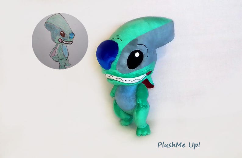 Peut inclure: Une peluche repr&eacute;sentant une cr&eacute;ature extraterrestre bleue et verte avec de grands yeux noirs et un large sourire. Un dessin du m&ecirc;me personnage est dans un cercle en haut &agrave; gauche. Le texte "PlushMe Up!" est en bas &agrave; droite.