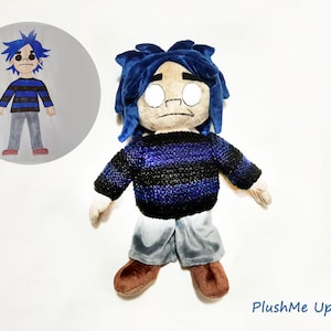 May include: A plush doll of a cartoon character with blue hair and a blue and black striped sweater. The doll has gray shorts and brown shoes. A smaller illustration of the character is in a circle in the upper left corner.
