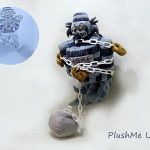 May include: A plush figure of a ghostly prisoner with a striped uniform, chains, and a ball and chain. The figure has a menacing expression and is in a seated position. The image includes a sketch of the figure in a blue circle.