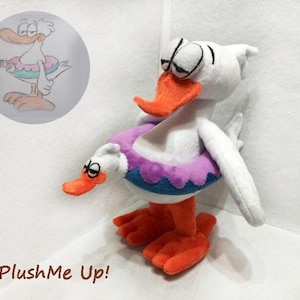 May include: A plush white duck toy with an orange beak and feet, wearing a purple and blue inflatable ring. The toy has a cartoonish design, with a matching illustration in a circle. The text "PlushMe Up!" is at the bottom.