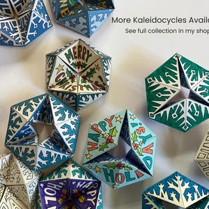 May include: A collection of paper kaleidocycles featuring various holiday designs, including snowflake patterns and text reading Merry Christmas and Happy Holidays. The geometric shapes are colored in shades of blue, green, and white, with some uncolored outlines.