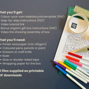 May include: A printable PDF craft kit featuring a black and white line art kaleidocycle template with holiday motifs, a metal ruler, a roll of tape, a glue stick, scissors, and a set of colorful markers on a green cutting mat with text instructions.