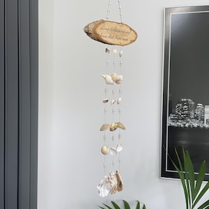 May include: A hanging seashell wind chime. The top is a wooden plaque with the text "Listen to the wind and know that I am near". Various seashells and beads are strung together, creating a decorative and calming effect.