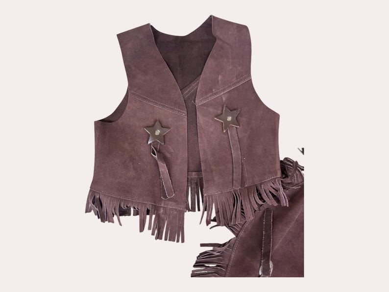 May include: A brown suede vest with fringe and star-shaped embellishments. The vest is part of a cowboy costume.