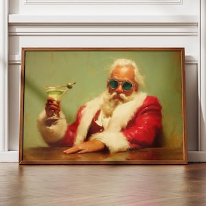 May include: A framed print depicts Santa Claus in a red suit with white fur trim, wearing green sunglasses, holding a martini with an olive. The artwork has a vintage, painterly style, set against a muted green background.