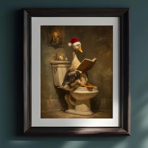May include: Framed art print featuring a goose wearing a Santa hat and reading a book while seated on a toilet. The artwork has a vintage aesthetic with a dark, moody color palette. Candles and a wall-mounted candle holder are visible in the background.