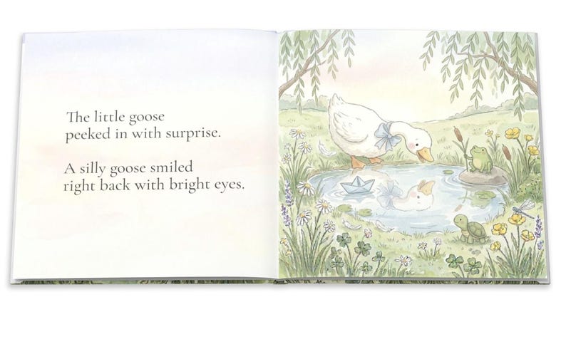 May include: An open book with a watercolor illustration of a goose looking into a pond. The text reads, "The little goose peeked in with surprise. A silly goose smiled right back with bright eyes."