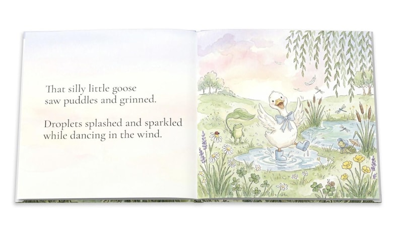 May include: An open book with watercolor illustrations. The right page shows a white goose in blue boots splashing in a puddle, with a frog and other details. Text on the left page reads: "That silly little goose saw puddles and grinned. Droplets splashed and sparkled while dancing in the wind."