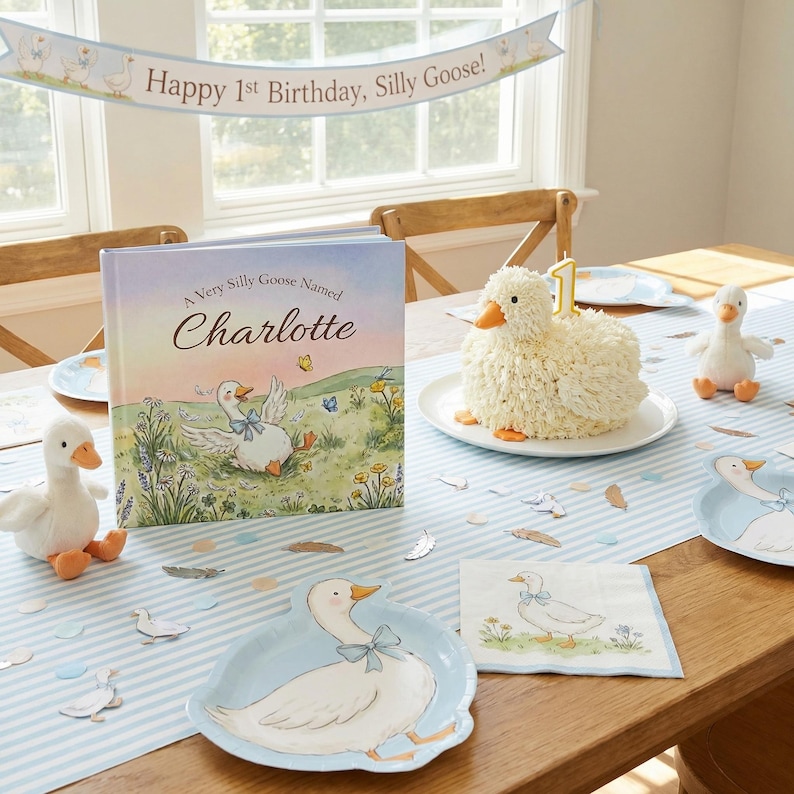 May include: A children's birthday party scene with a goose theme. Includes a cake, book, plush toys, plates, and a banner that reads "Happy 1st Birthday, Silly Goose!" The book is titled "A Very Silly Goose Named Charlotte."
