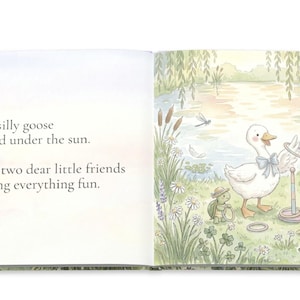 May include: A children's book illustration featuring a white goose with a blue bow tie playing a ring toss game with a frog and a turtle. The text reads: "Our silly goose played under the sun. With two dear little friends making everything fun."