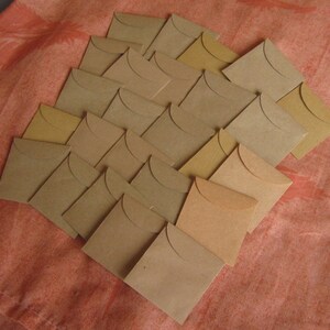 May include: A collection of twenty-five brown paper envelopes arranged in a staggered pattern. The envelopes are all the same size and shape, and they are made of a sturdy, textured paper.