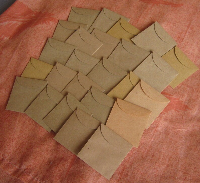 May include: A collection of twenty-five brown paper envelopes arranged in a staggered pattern. The envelopes are all the same size and shape, and they are made of a sturdy, textured paper.