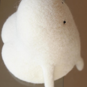 K&ouml;nnte beinhalten: Ein wei&szlig;es, flauschiges Filzspielzeug in Form einer Wolke mit zwei kleinen Armen. Das Spielzeug hat zwei schwarze Augen.