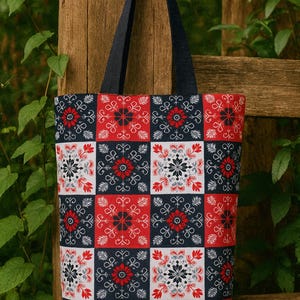 以下が含まれることがあります： 赤、白、ネイビーブルーの正方形が繰り返されるパターンのトートバッグ。各正方形には花の模様があります。ネイビーブルーのハンドルが付いており、様々なアイテムを持ち運ぶのに適した丈夫な生地で作られています。