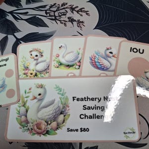 May include: A collection of cards with swan illustrations and text. The cards feature a pink border and various designs, including swans with floral crowns and text that reads "I love Saving! Roll & Save" and "Feathery Nest Saving Challenge".