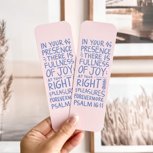 May include: Two pink bookmarks with rounded corners are held up. Each bookmark has blue text that reads "In your presence there is fullness of joy; at your right hand are pleasures forevermore. Psalm 16:11."