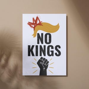 May include: White poster with the words "NO KINGS" in bold black letters. The poster features a stylized blonde hairstyle with a red crown and a black fist with yellow rays.