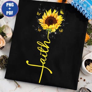 Op de afbeelding: Een zwarte rechthoekige grafische print met een grote gele zonnebloem met een donkerbruin hart, omringd door kleine gele vlinders en witte glinsteringen. Het woord faith staat in een geel cursief lettertype onder de zonnebloem.