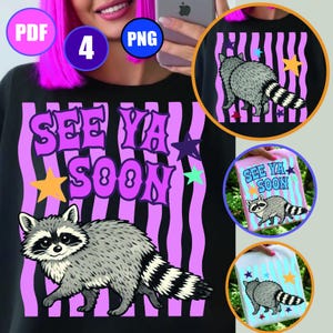 May include: A black t-shirt featuring a graphic of a grey raccoon with a striped tail, set against a background of vertical wavy purple stripes. The text "SEE YA SOON" is printed in a bold purple font, accented by small yellow, purple, and teal stars.