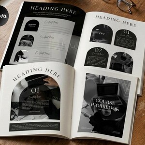 May include: Open book with black and white design elements. The pages feature headings, content sections, and the text "COURSE WORKBOOK". The book is on a wooden surface with a pen and glasses.