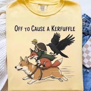 May include: Yellow t-shirt with the phrase "Off to Cause a Kerfuffle" in black text. The graphic features a corgi, fox, turtle, and raven. The corgi is wearing a harness, the fox is wearing a cape, and the turtle is wearing a construction hat.