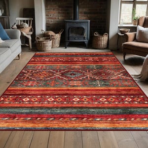 May include: A rectangular area rug with a geometric pattern in shades of red, orange, green, and blue. The rug features a central diamond design and horizontal stripes. The rug is placed on a wooden floor in a living room setting.