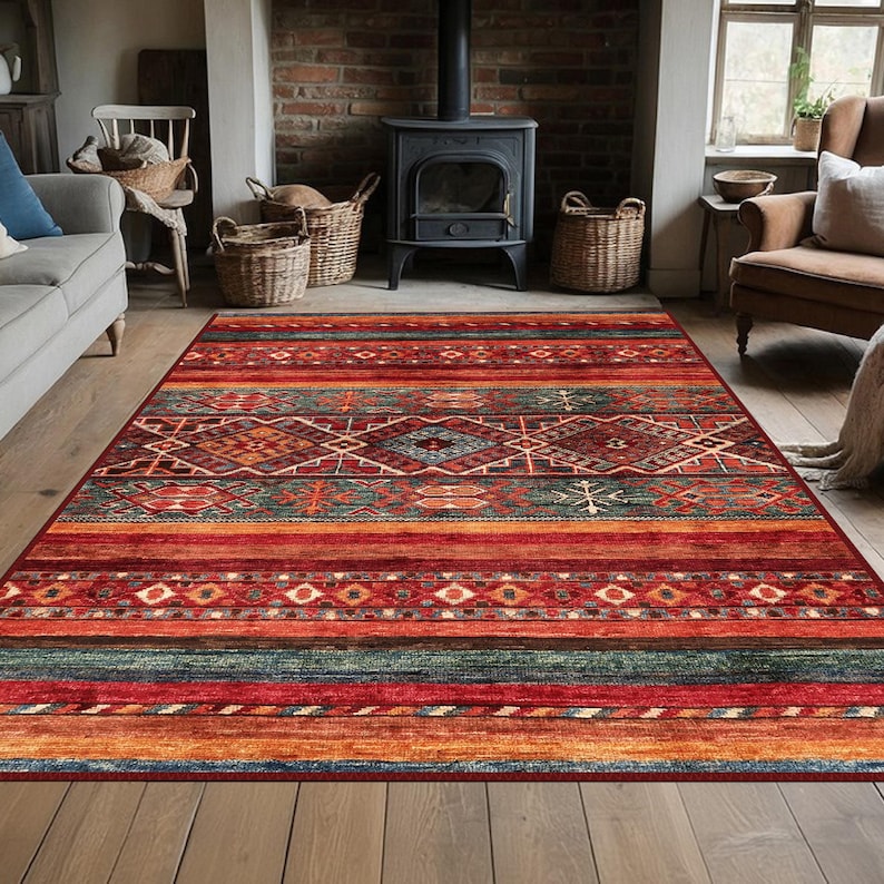May include: A rectangular area rug with a geometric pattern in shades of red, orange, green, and blue. The rug features a central diamond design and horizontal stripes. The rug is placed on a wooden floor in a living room setting.