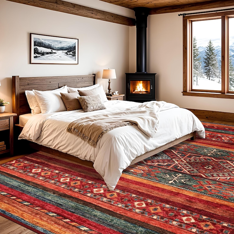 May include: A bedroom with a wooden bed, white bedding, and a colorful rug. The rug features a geometric pattern with red, orange, and green stripes. A fireplace and a window with a snowy mountain view are also visible.