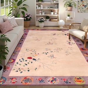 May include: A large rectangular rug with a light peach center and a lavender border. The rug features a floral design with red, blue, and green flowers and branches. The border has circular patterns with colorful floral motifs.