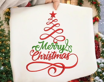 Könnte beinhalten: Ein weißes Kissen mit einem roten, gestickten Weihnachtsbaum-Design und den Worten "Merry Christmas" in roter und grüner Schrift. Das Kissen wird von einer Hand gehalten.